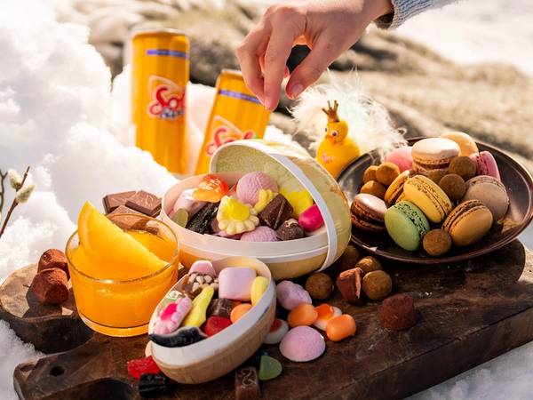 Påskegodt og påskeegg på et trebrett ute i snøen.