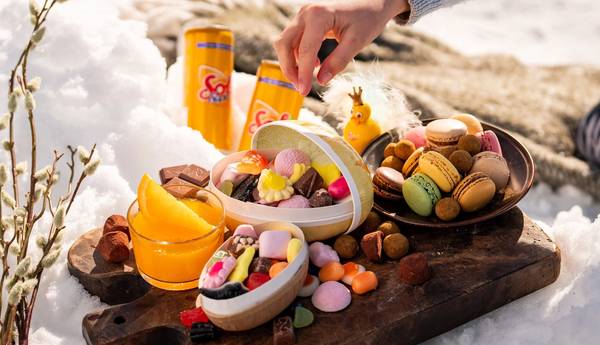 Påskegodt og påskeegg på et trebrett ute i snøen.