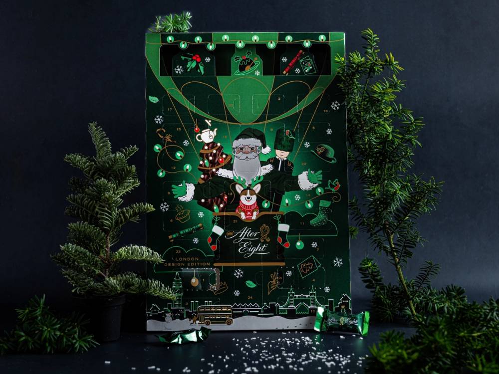 En julekalender med en julemannfigur som holder en gave, omgitt av grønne planter og julepynt, på en mørk bakgrunn.