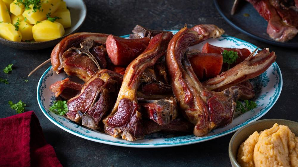 Pinnekjøtt med kokte poteter og grønnsaker på et serveringsfat.