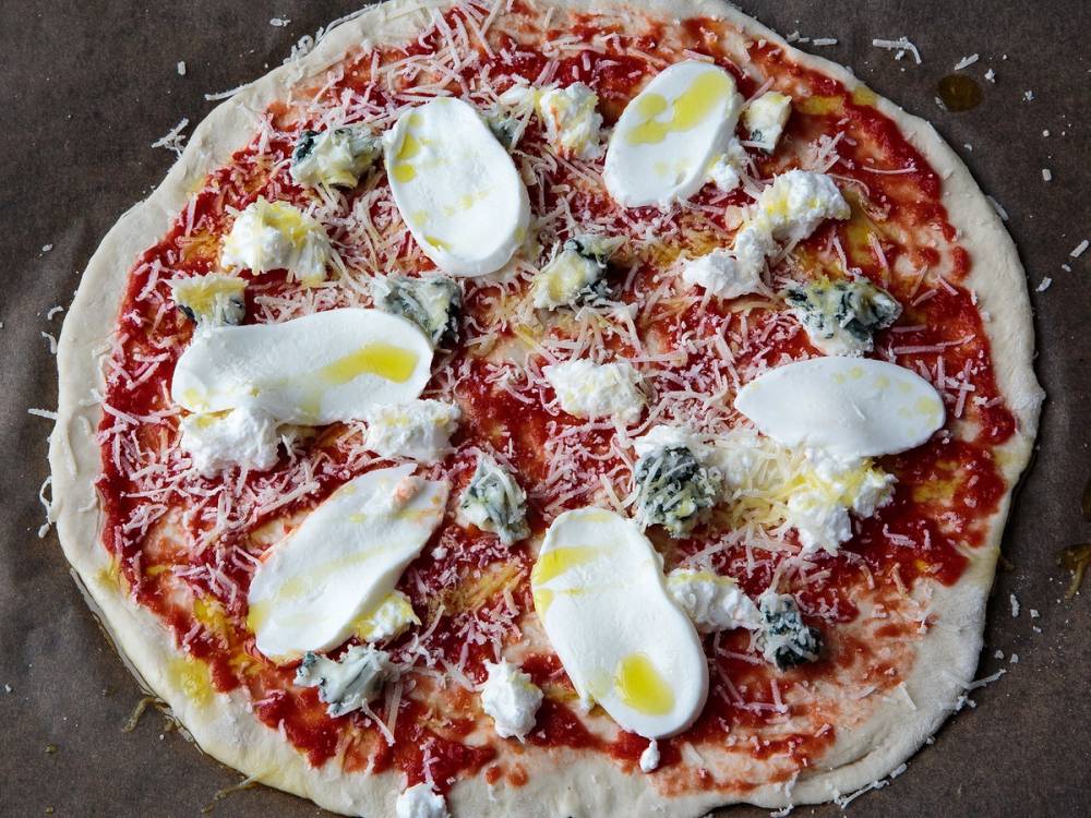 Pizza med ost, skinke, sopp og ruccola på toppen, ferdig stekt og klar til servering.