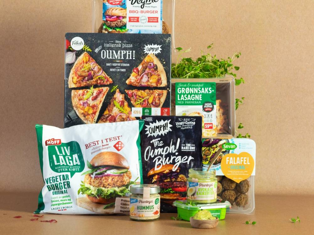 Et utvalg av plantebaserte matvarer og grønnsaker som fremmer bærekraft, inkludert ferdigretter, burgere og grønnsaker, på et bord.