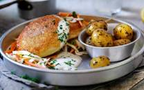 Fiskekaker med råkostsalat og små poteter på en tallerken.