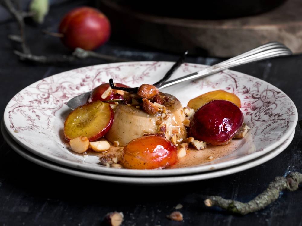 Panna cotta med kaffe og stekte plommer på en dekorativ tallerken.