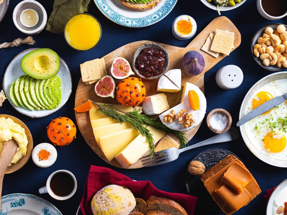Et julefrokostbord med vegetariske retter og pålegg, inkludert ost, frukt og kjeks.