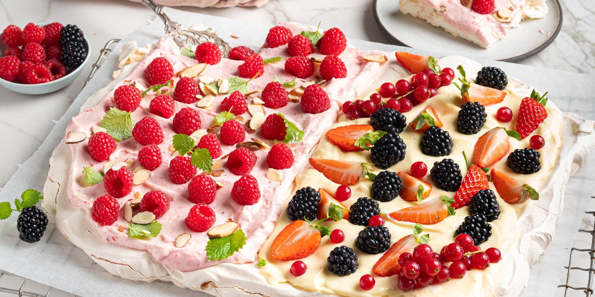 To store pavlovaer med krem og friske bær, plassert på et hvitt bord.