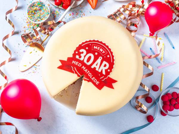 En marsipankake med en logo som feirer Menys 30-årsjubileum, omgitt av festpynt og ballonger.