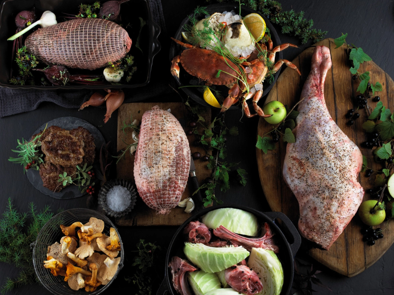 Ulike råvarer som kjøtt, grønnsaker og sopp er presentert på et bord, klare til å bli tilberedt.