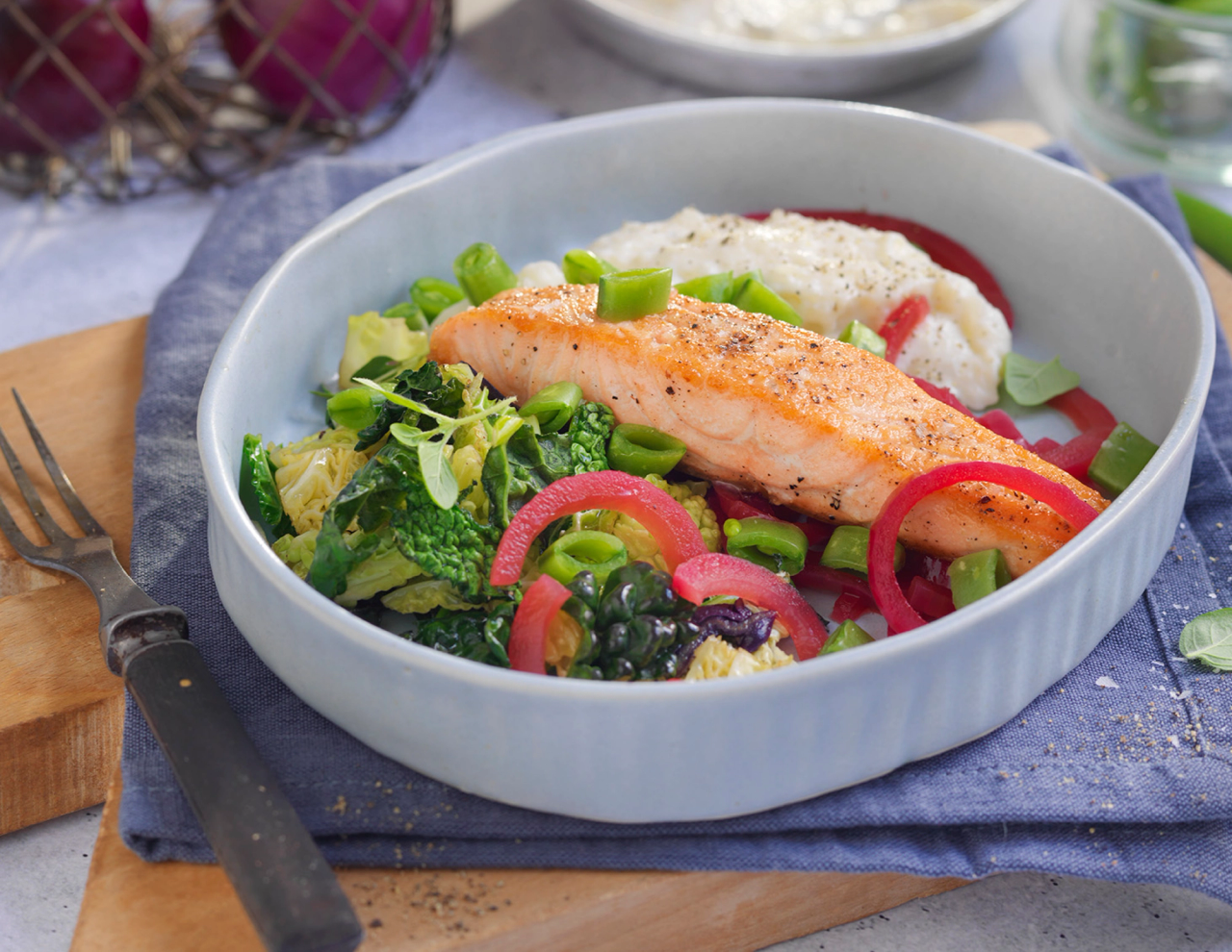 Laksefilet med blomkålpure og grønnsaker på en tallerken.