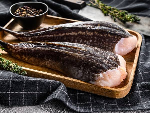 To breiflabb-halser på et treplatet med krydder og urter rundt, klar til tilberedning.