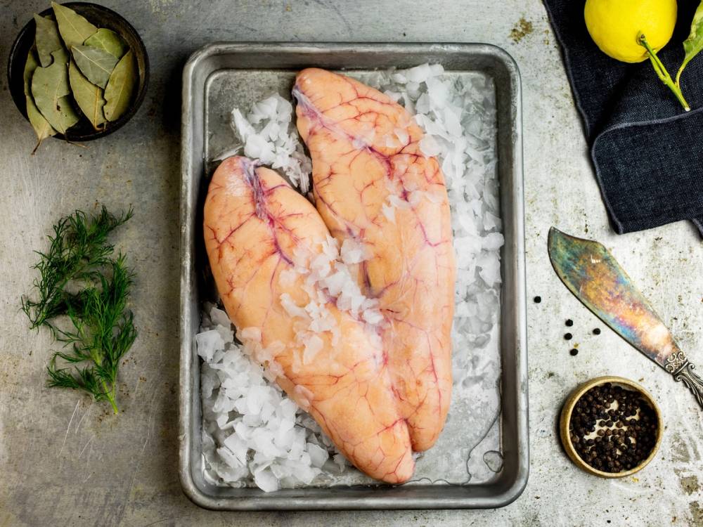 Torsk med rogn på et metallfat omgitt av is og urter, klar for tilberedning.