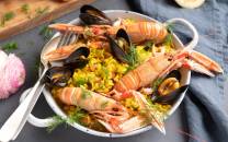 Paella med reker, blåskjell og grønnsaker på en tallerken.