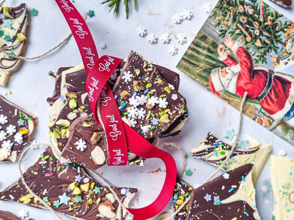 Sjokoladeplater dekorert med julepynt og pyntesnorer, med julekort i bakgrunnen