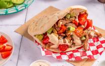 Kebab med strimlet lam, tomater og grønnsaker i pitabrød på et bord.