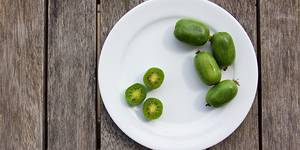 Kiwibær på en hvit tallerken, noen er skåret i skiver og viser grønn frukt med små svarte frø.