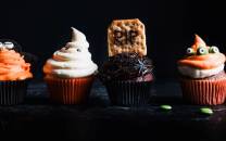 Fire cupcakes med halloween-tema dekorasjoner på en svart bakgrunn.