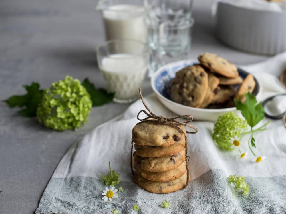 Stabel av cookies og skål med cookies på duk pyntet med blomster