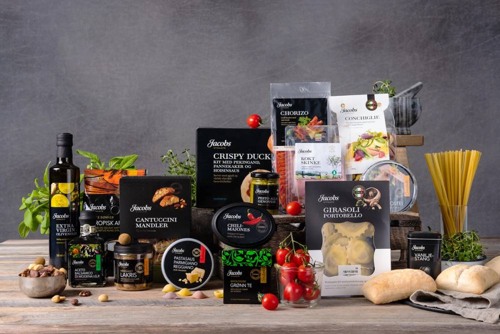 Et utvalg av matvarer og ingredienser, inkludert pasta, tomater, ost, kjøtt, og ulike krydder, lagt ut på en benk.