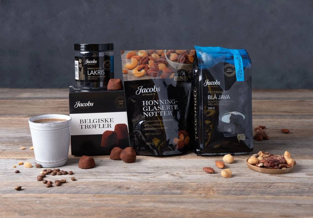 Ulike typer trøfler og kaffe på et bord, med emballasje fra Jacobs, inkludert belgiske trøfler og nøtter.