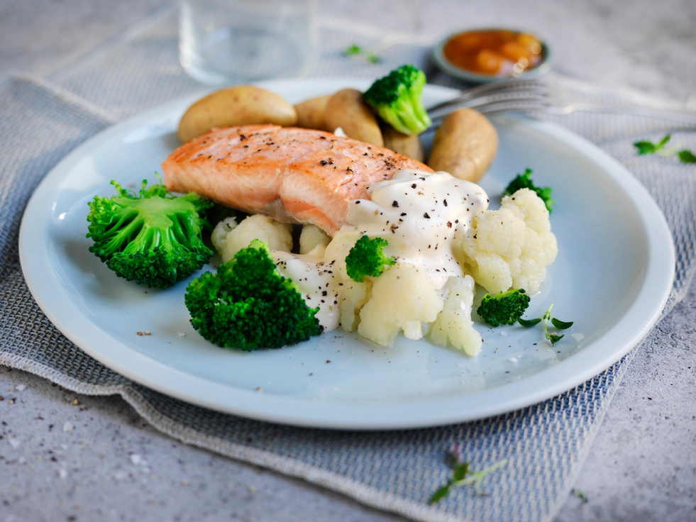 Laksefilet med saltkokte poteter og brokkoli på en hvit tallerken