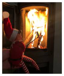 To julekosedyr foran en peis med brennende ild, hvor den ene har på seg en rød og hvit stripete genser og den andre har på seg en rød lue med hvit dusk.