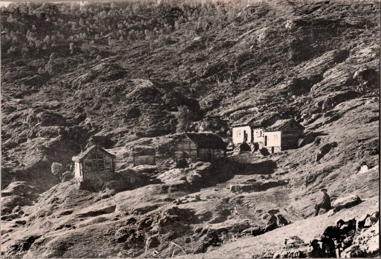 Et gammelt, retusjert bilde av Lundal med noen små bygninger på en fjellskråning.