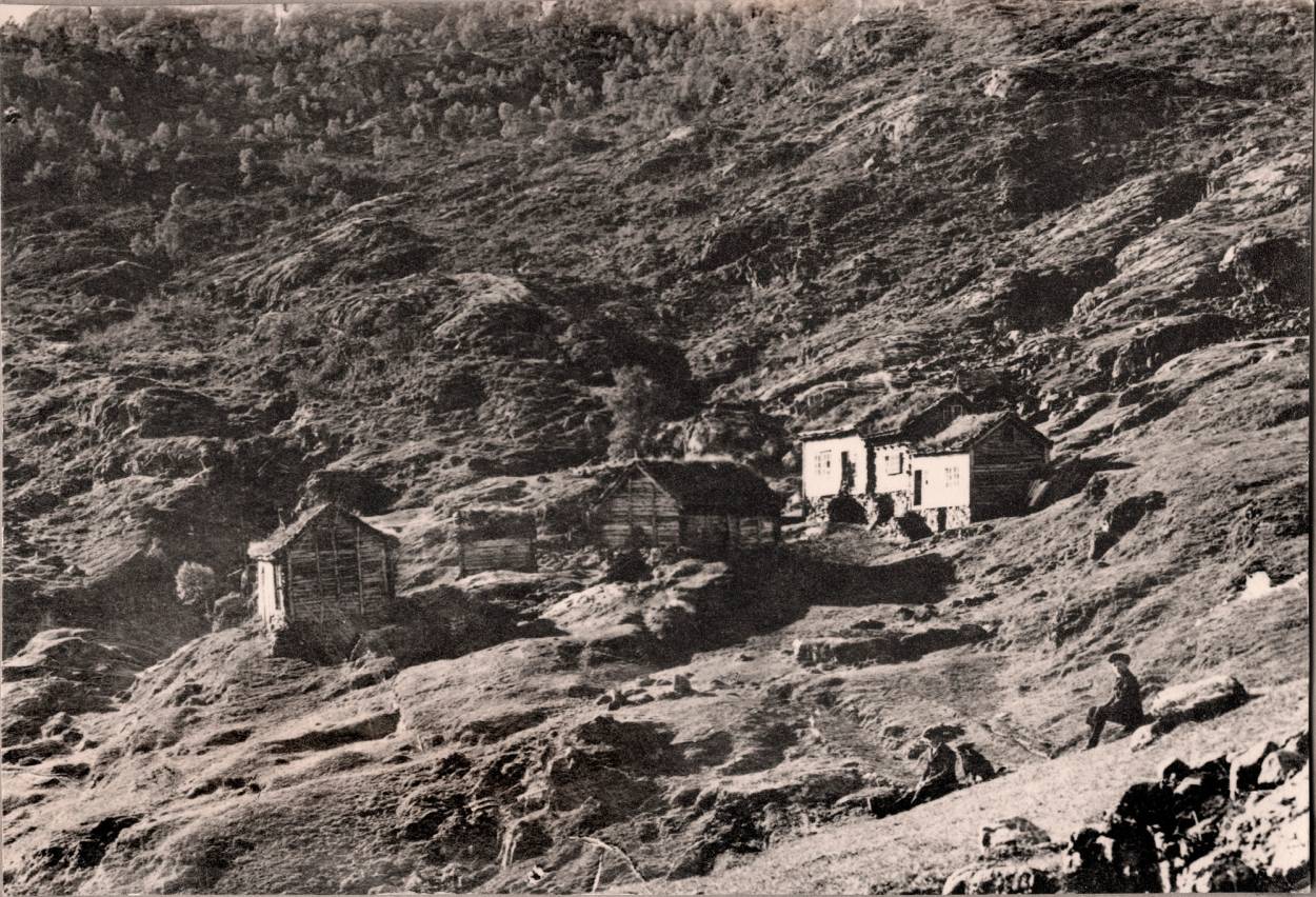 Et gammelt, retusjert bilde av Lundal med noen små bygninger på en fjellskråning.