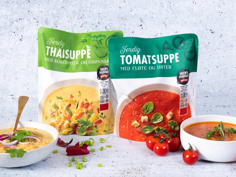 To poser med supperposer, en med grønnsaksuppe og en med tomatsuppe, omgitt av to skåler med ferdiglagde supper og noen tomater og urter.