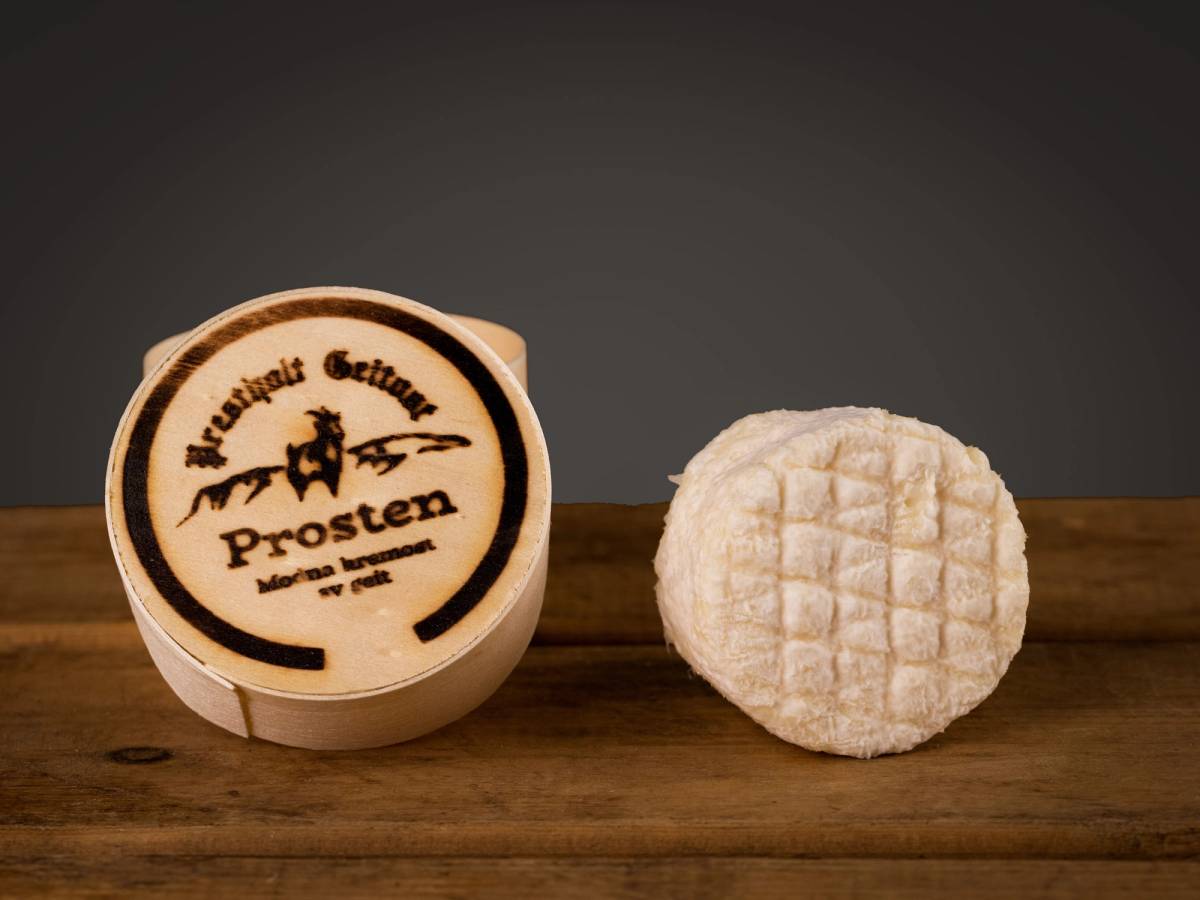 En ost med etikett som sier 'Prosten' og en rund ost med rutete mønster på toppen, plassert på en treplate.