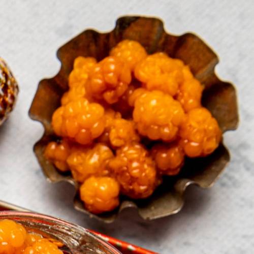 Små, gule multer i en papirform, klare til å spises, på et hvitt underlag.