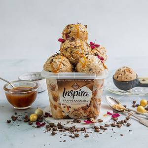 Hennig-Olsen Inspira Frappe Karamell iskrem med karamellsaus og kakebiter i en kopp, omgitt av kaffe- og sjokoladetilbehør.
