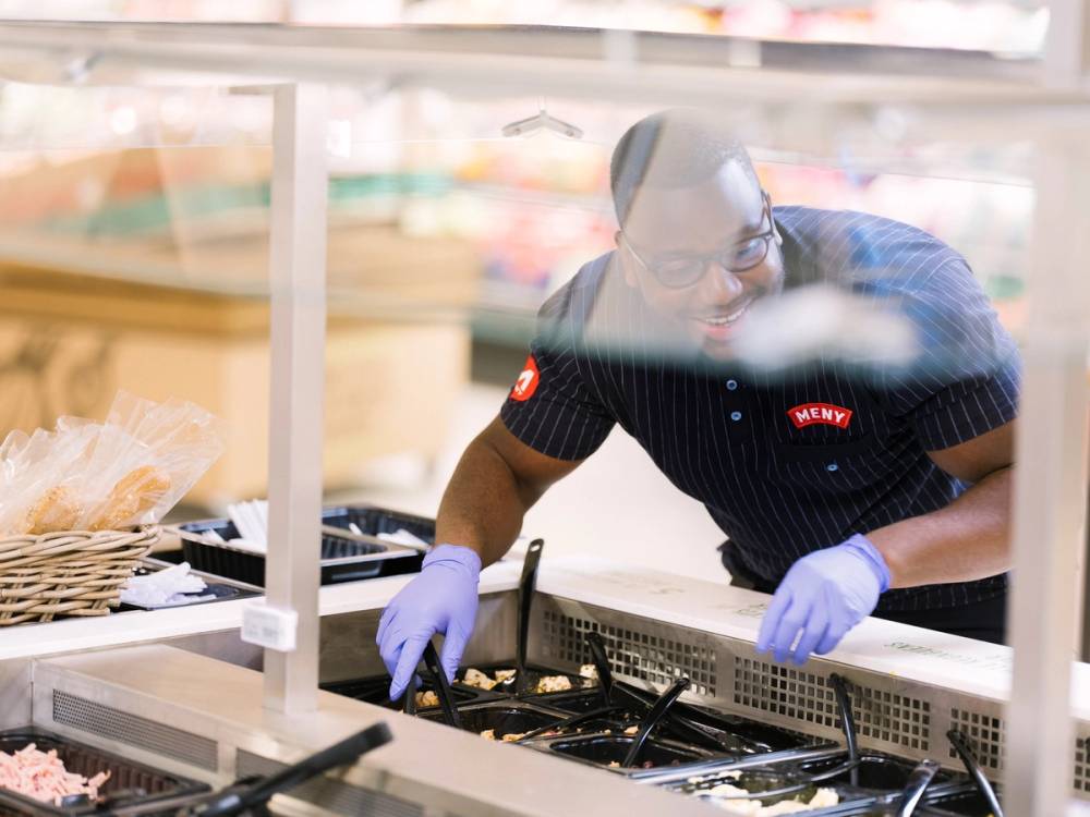 En person i arbeidstøy og hansker jobber med en gassovn på kjøkkenet.