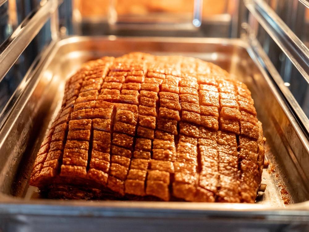 Et stort stykke karamellpudding med et rutete mønster på toppen ligger i en metallform.