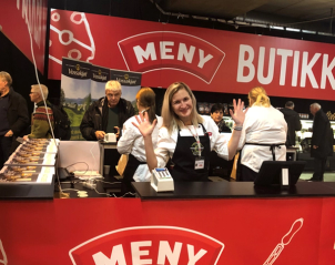 Kunder i kasseområdet på en butikk med en stor rød skilt som sier 'MENY BUTIKK'.