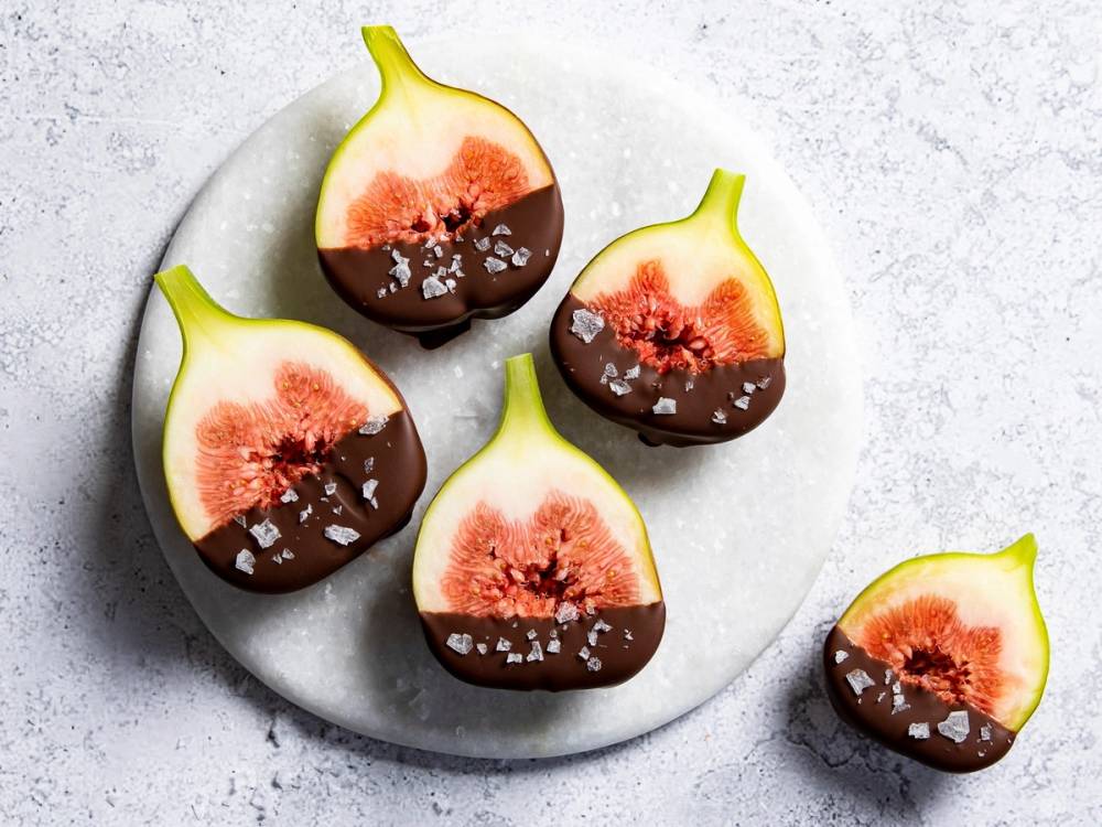 Fiken dyppet i sjokolade med havsalt på en hvit tallerken