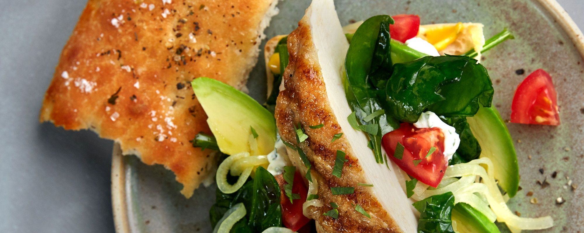 Kyllingfilet i focacciabrød med salat og cherrytomater på en tallerken