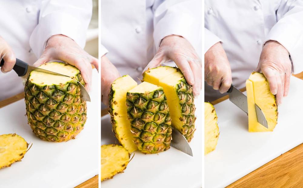 En person skjærer i en fersk ananas på et skjærebrett, med en kniv i hånden.