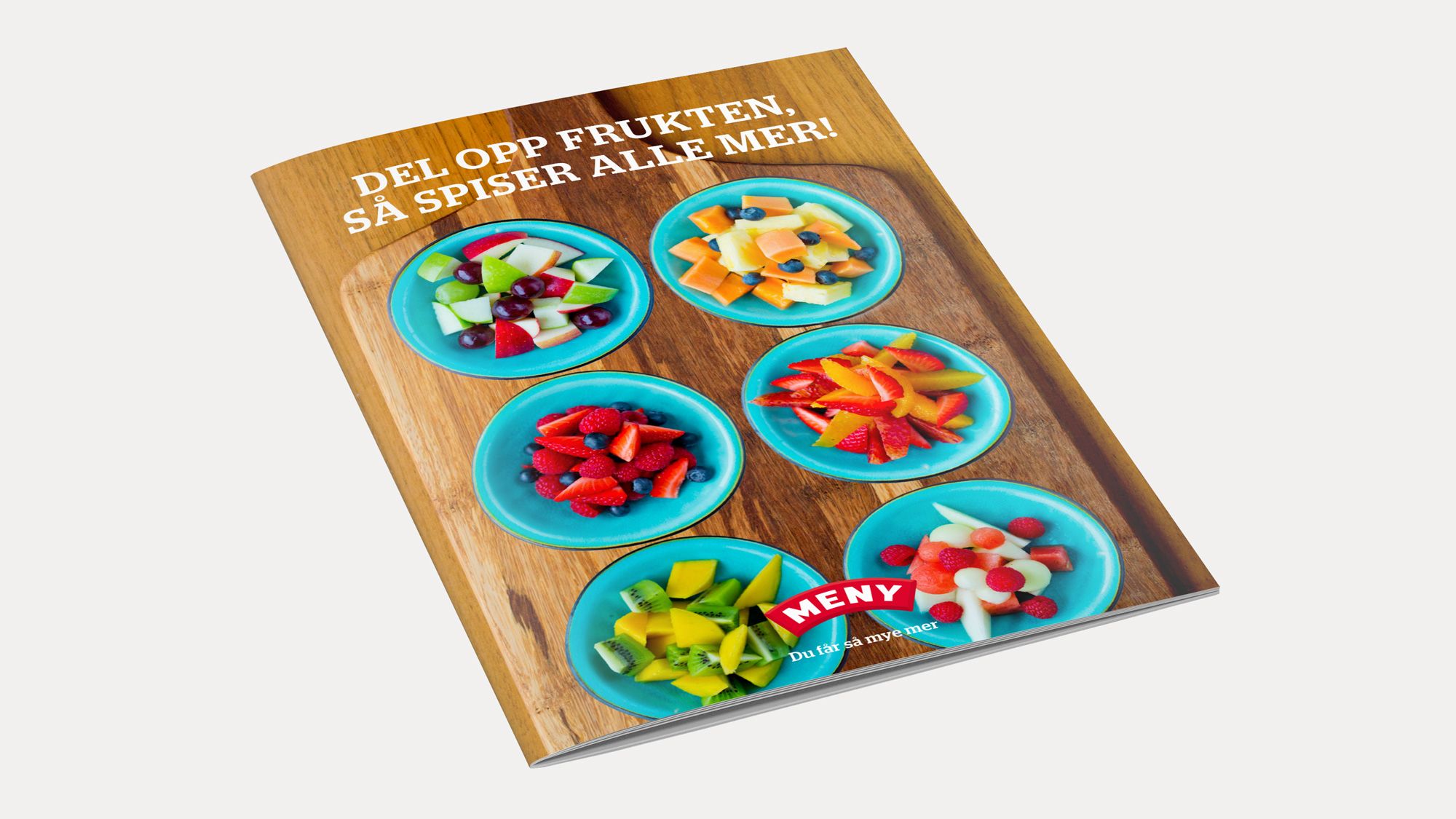 En bok eller plakat med bilder av ulike frukter og teksten 'Del opp frukten, så spiser alle mer!'