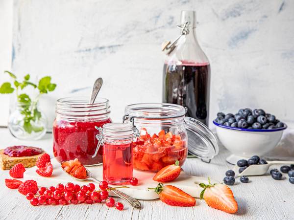 Bilde av ulike bær og hjemmelaget saft i glass og skåler, klare til sylting og safting.