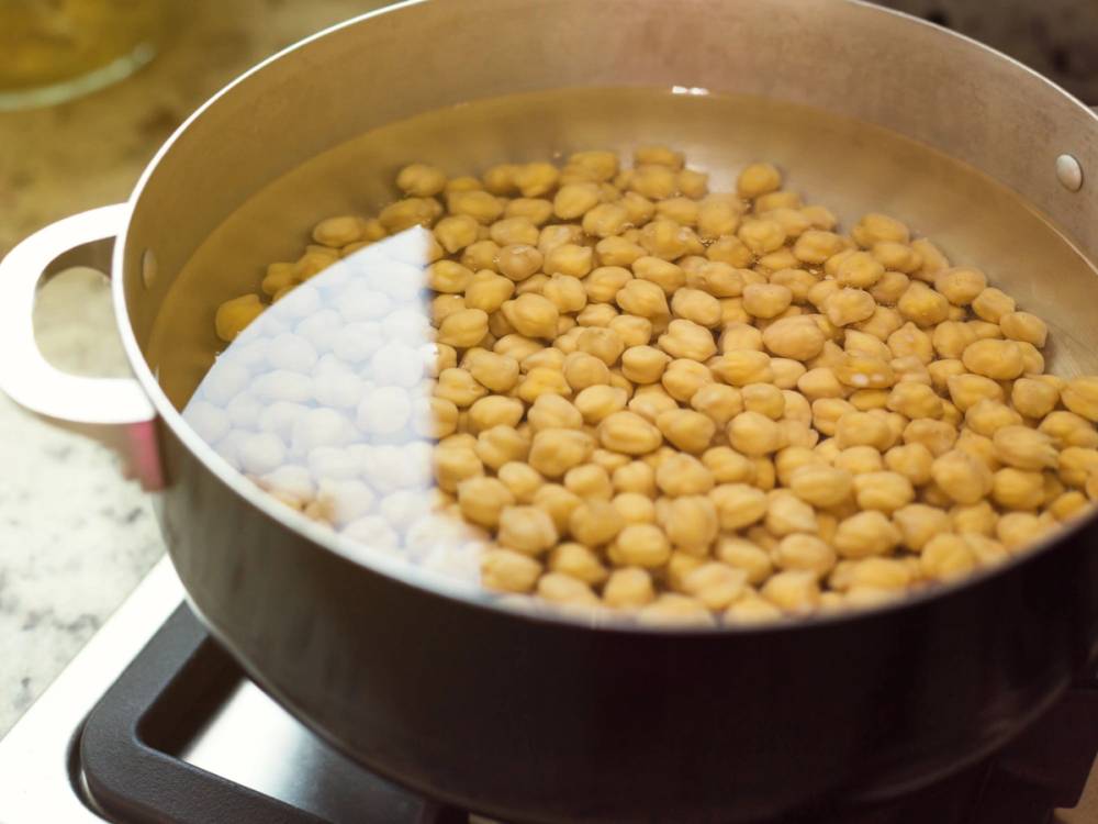 Kikerter som kokes i en stor gryte på komfyr