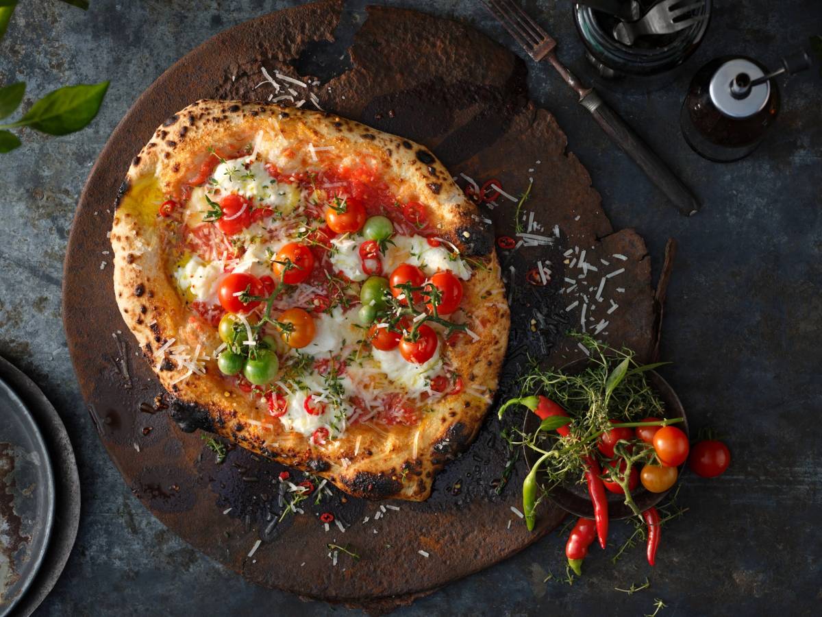 Pizza med tomater, mozzarella og basilikum på en treplate