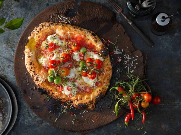 Pizza med tomater, mozzarella og basilikum på en treplate