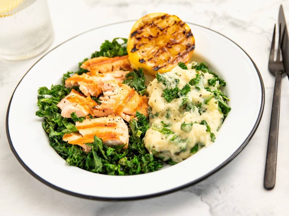 Colcannon med stekt laks og en liten grillede maiskolbe på en hvit tallerken