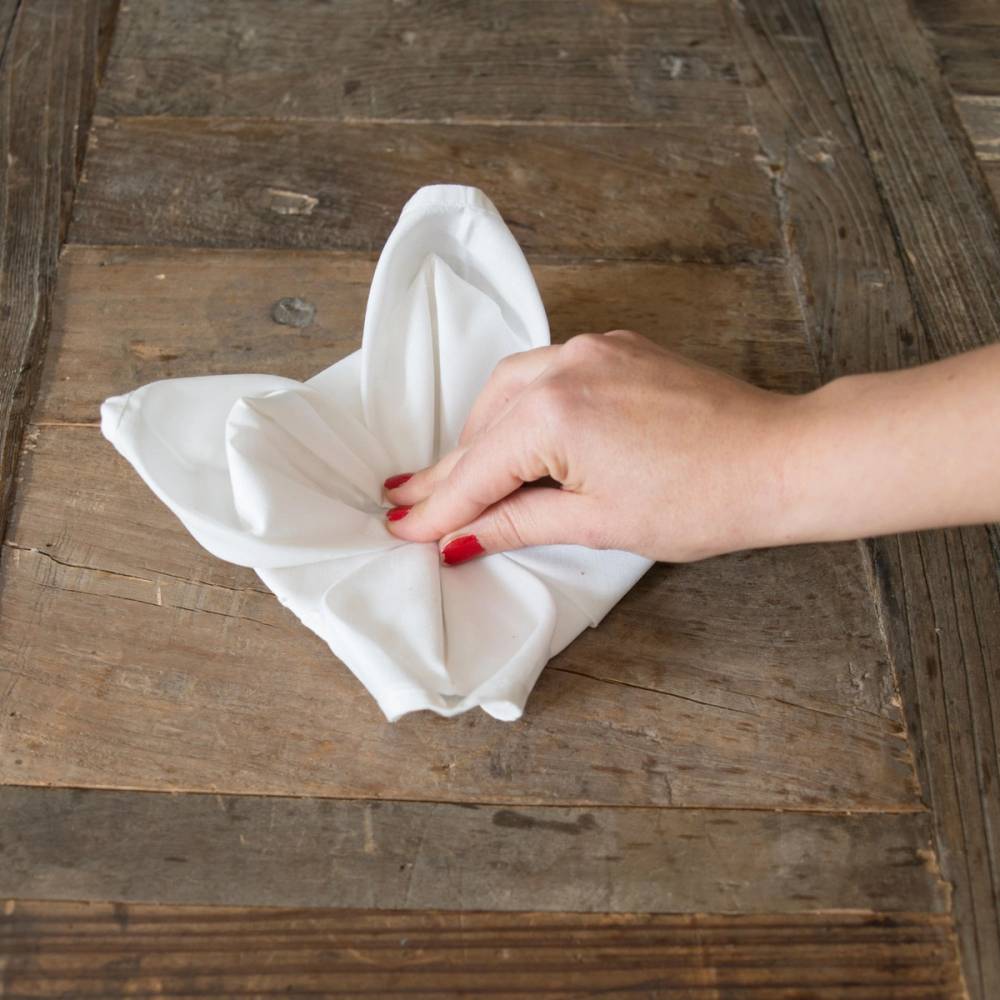 En person som folder en hvit serviett på et trestykke bord til jul.