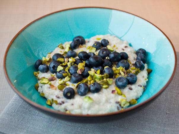 Havregrøt toppet med blåbær og hakkede pistachnøtter i en blå skål