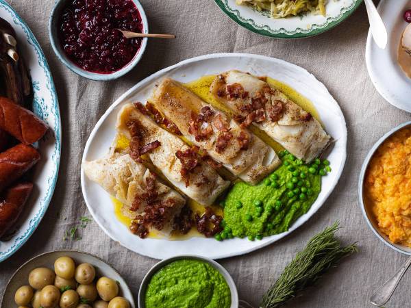 Lutefisk servert med grønnsaker og tilbehør på et fat, sett fra oven.