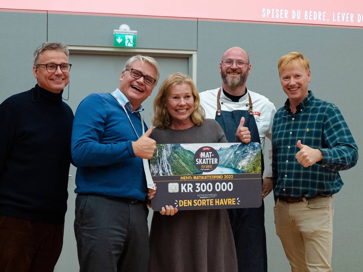 Fem personer står sammen og holder et stort sjekk for Matskattstipendet 2022, med en person i midten som viser tommel opp.