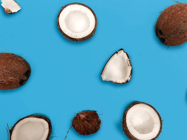 Kokosnøtter, noen hele og noen delt i to, mot en blå bakgrunn