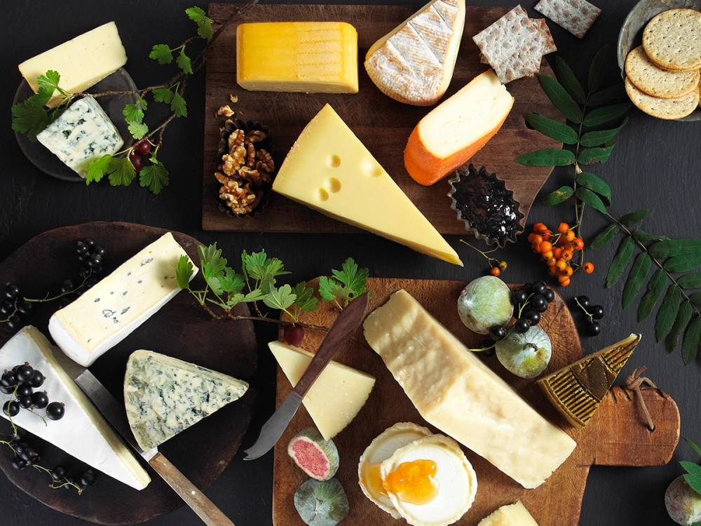 Ulike oster av ulike typer og farger er plassert på et bord med grønne blader og små dekorasjoner rundt.