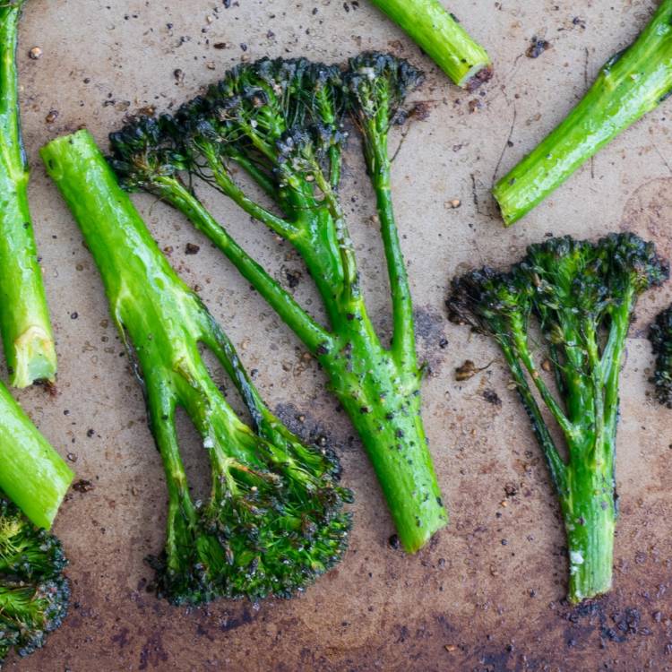 Grønne brokkolibiter ligger på en stekeplate, klare til å bli stekt eller kokt.